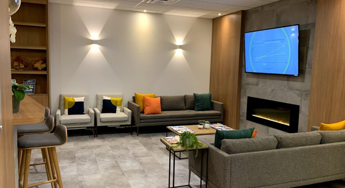 The image shows an interior space with modern furniture, including seating and a fireplace, and a television mounted on the wall displaying a blue screen.