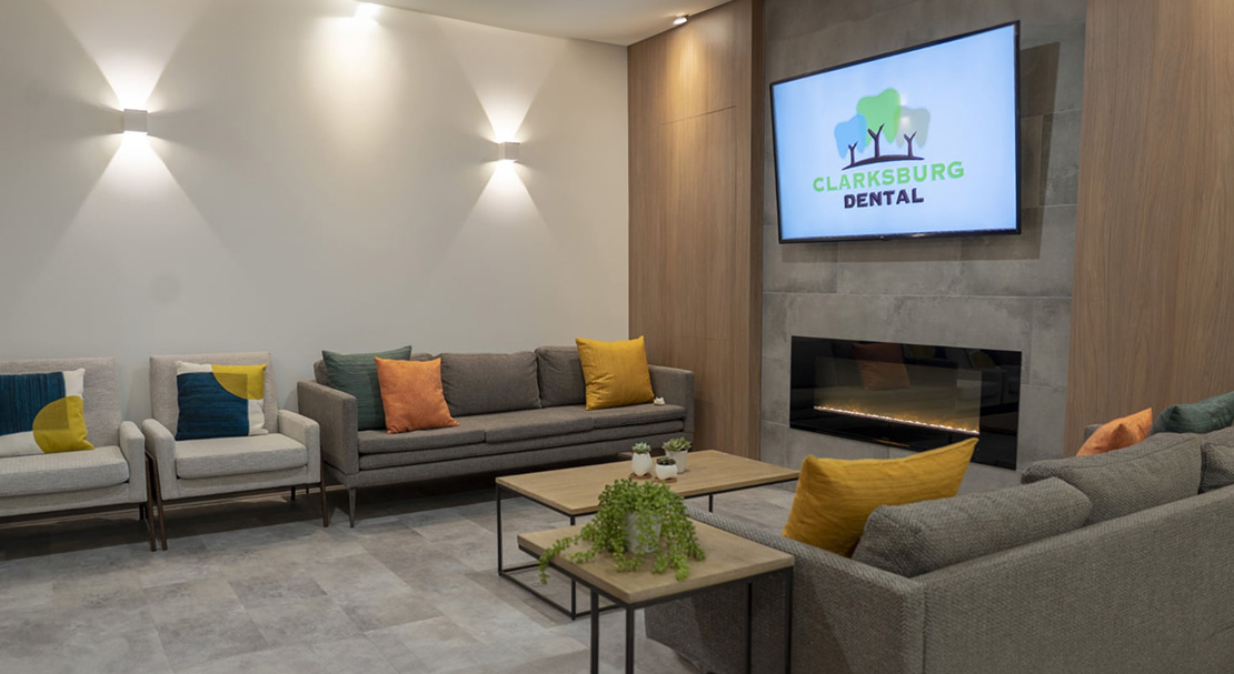 The image shows a modern interior space with a fireplace, seating area, and a television displaying a logo for  Dental 360.