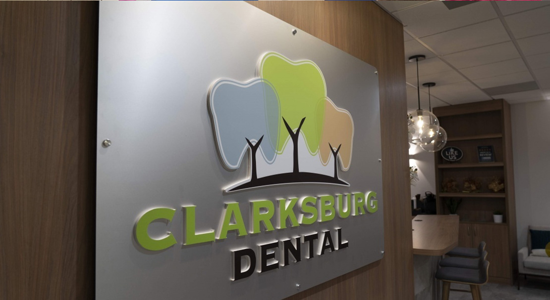 The image shows an interior space with a signage board featuring a logo and text, including the name  Clarksville Dental  and a graphic of a tree, within a modern office environment.