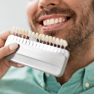 A man holding a toothbrush with toothpaste on his teeth while smiling.