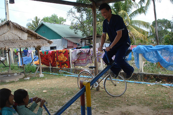 Man on bicycle riding down slide in yard.