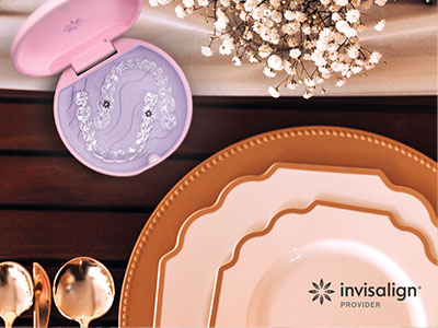 The image shows a table setting with various items including plates, bowls, a cake box, and other decorative items, with the focus on a pink box of dental floss, suggesting a promotional context for oral hygiene products.